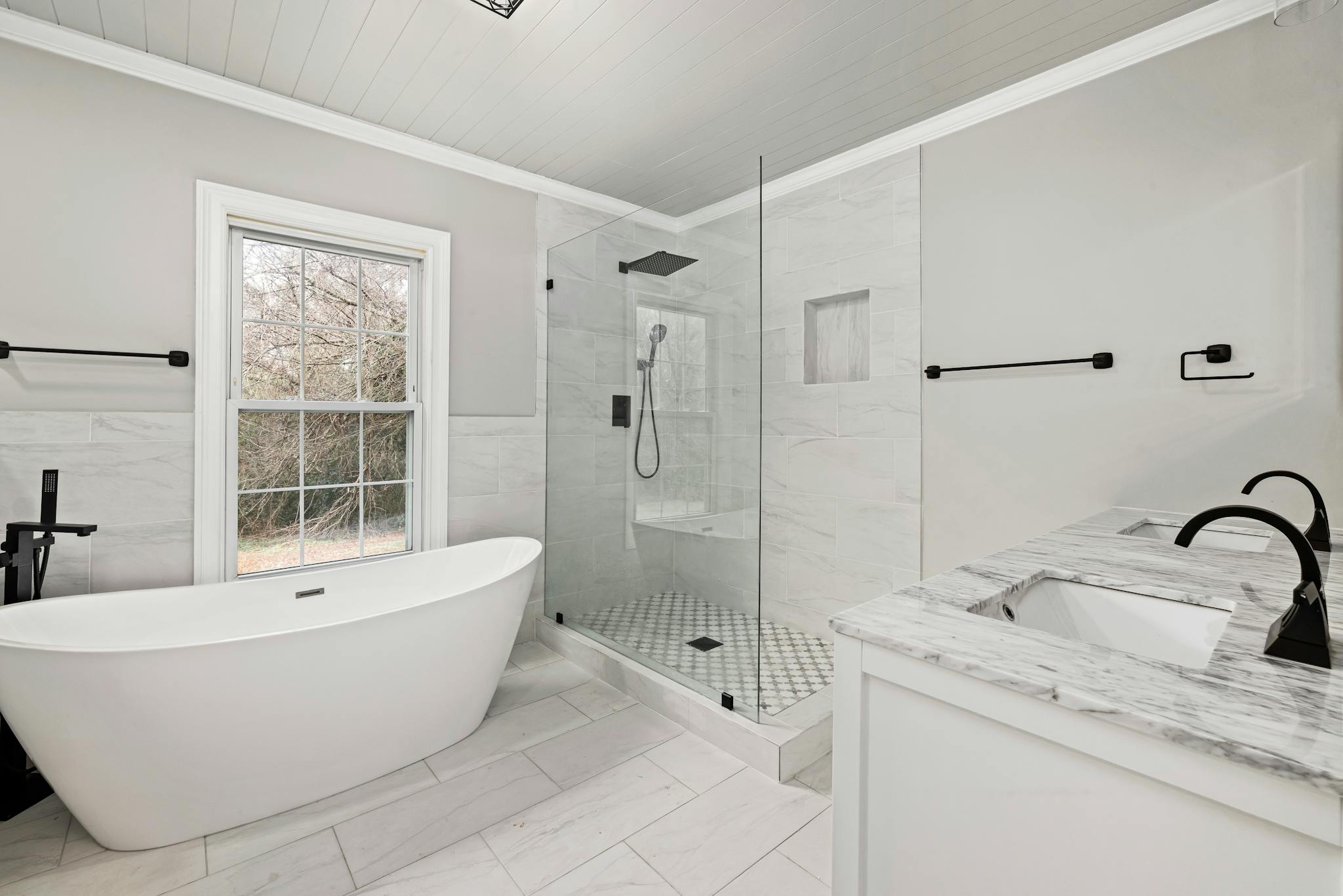 Sleek bathroom featuring a freestanding tub, glass shower, and marble accents.